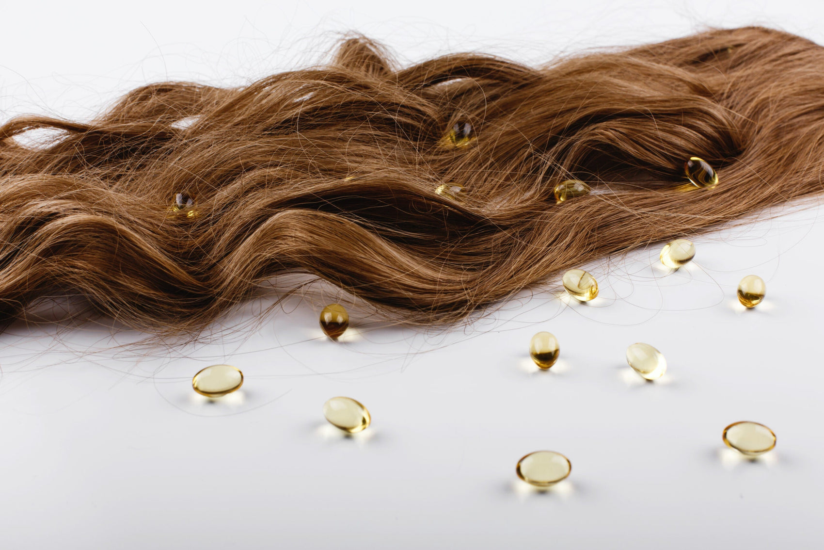 Oil capsules with viatamin E lie on brown hair curls